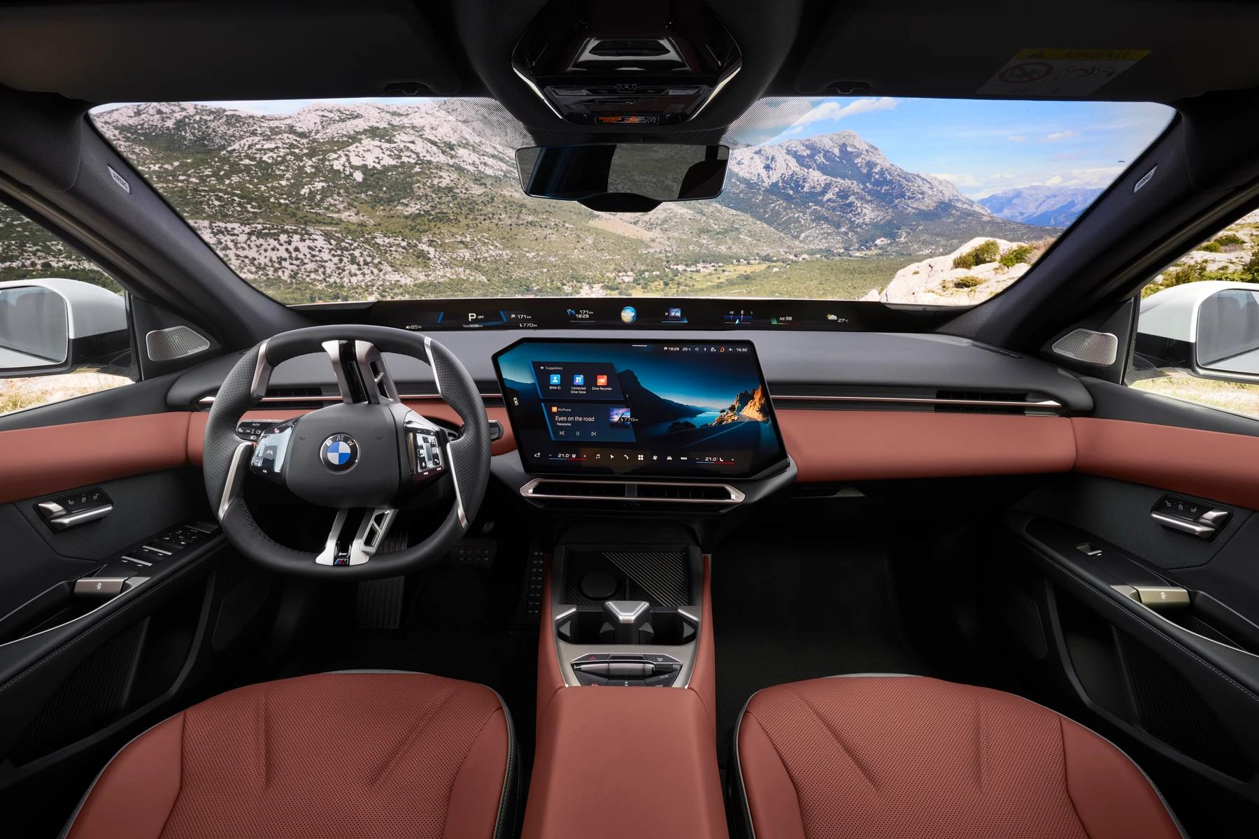 Wide view across the BMW i3 cabin, showing the steering wheel, center display and front seats.
